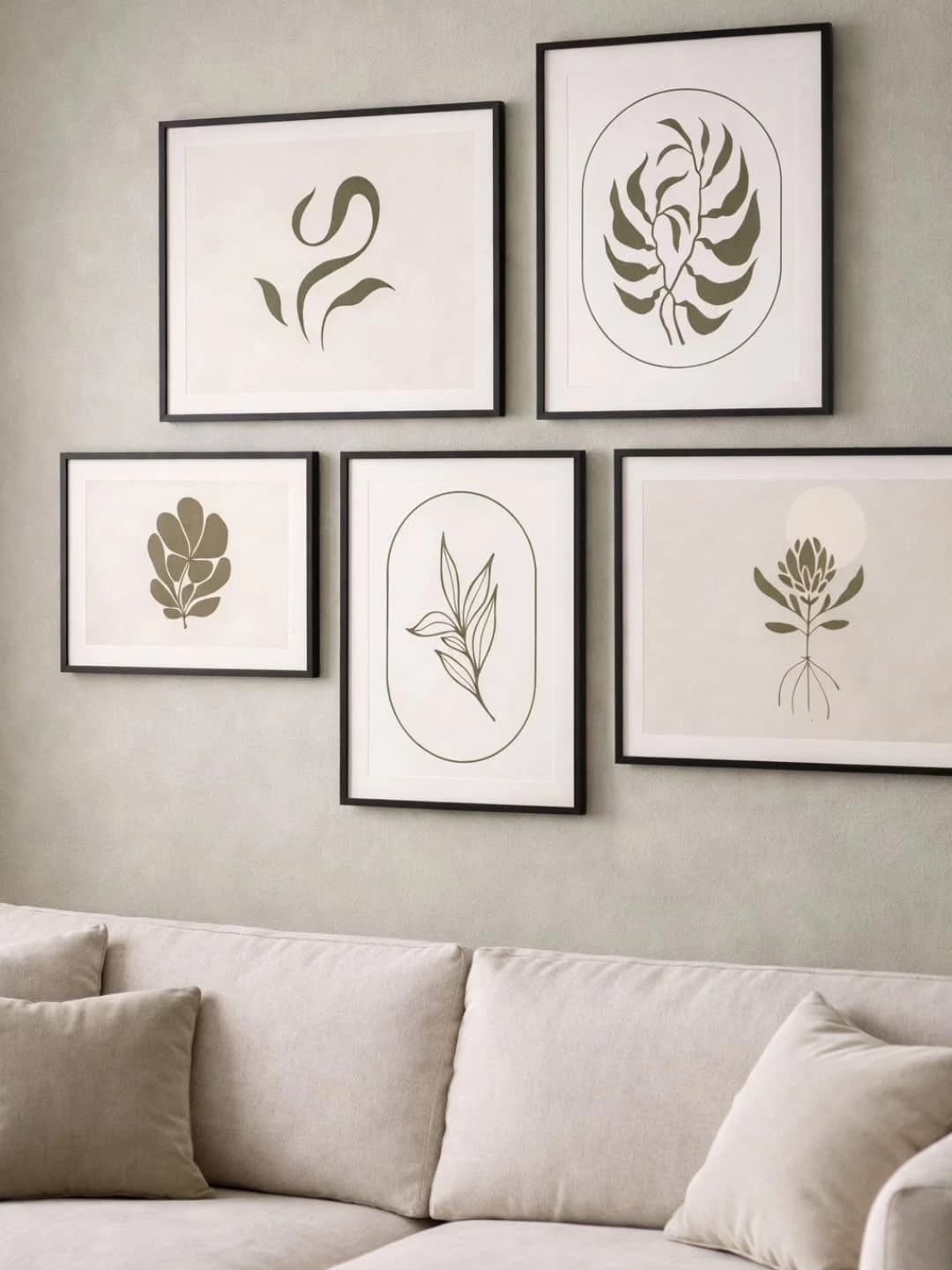 Five black-framed prints of olive-green botanical and leaf motifs arranged as a gallery wall above a beige sofa with matching cushions.